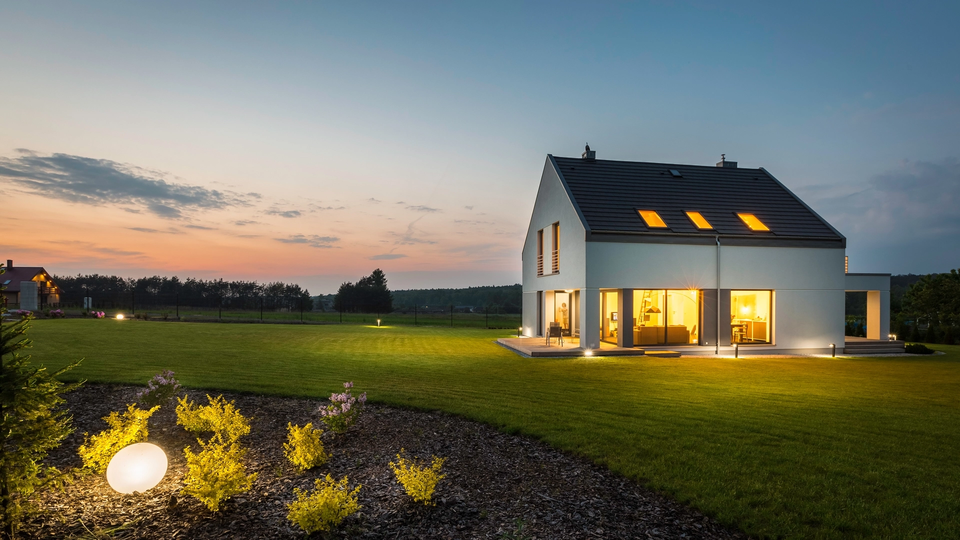 Een wit huis in de achtergrond met een zeer nette en goed verzorgde tuin. Het gras is vers gemaaid.